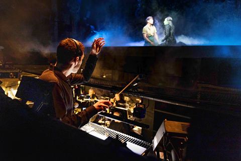 Wicked London Musical Director Ron Crocker conducting from the keyboard in the orchestra pit during a performance. Photo by Mark Senior